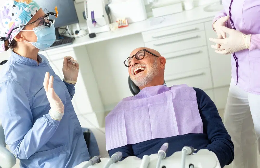 Who Benefits Senior man laughing and engaging in conversation with his Plaza Dental dentist